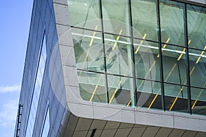 Modern buildings of unusual forms from glass and metal. Geometry of lines and curves. The inclined facade. Blue sky.