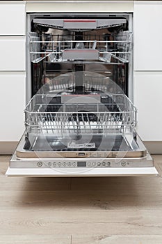 Modern built-in empty dishwasher with open door