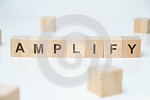 Modern business buzzword - amplify. Word on wooden blocks on a white background photo