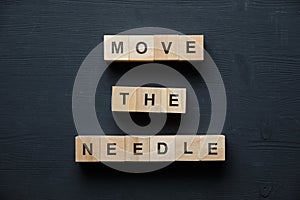 Modern business buzzword - move the needle. Top view on wooden table with blocks. Top view