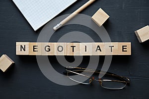 Modern business buzzword - negotiate. Top view on wooden table with blocks. Top view