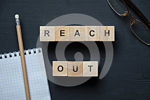 Modern business buzzword - reach out. Top view on wooden table with blocks. Top view