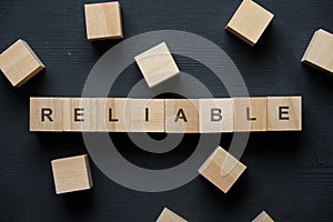 Modern business buzzword - reliable. Top view on wooden table with blocks. Top view