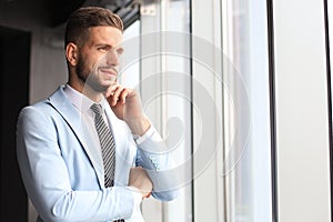 Modern business man in formalwear standing near window in the office