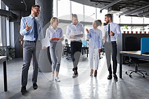 Modern business people discussing business and smiling while walking through the office corridor