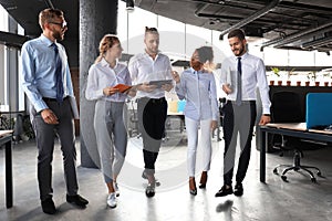 Modern business people discussing business and smiling while walking through the office corridor