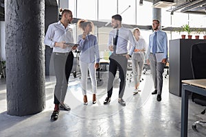 Modern business people discussing business and smiling while walking through the office corridor