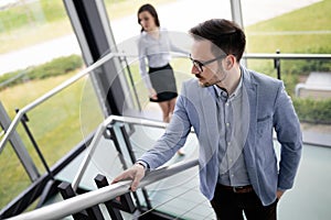 Modern business people walking on stairs in glass hall in office building