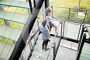 Modern business people walking on stairs in glass hall in office building