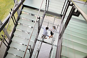 Modern business people walking on stairs in glass hall in office building