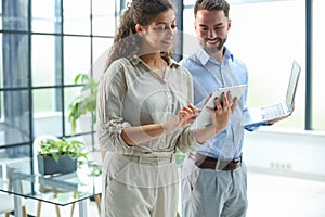 Modern business people are working using laptop and smiling while standing in the office.