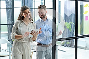 Modern business people are working using laptop and smiling while standing in the office.