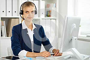 Modern business woman with headset in the office. Customer service operator at home work place. Success start up concept