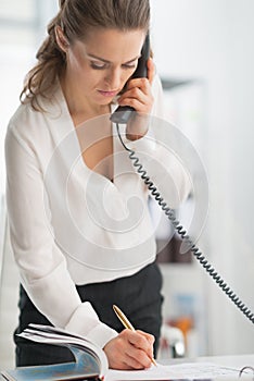 Modern business woman in office talking phone