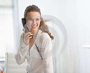 Modern business woman in office talking phone