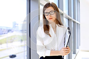 Modern business woman standing and keeping papers in the office with copy space area