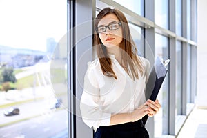 Modern business woman standing and keeping papers in the office with copy space area