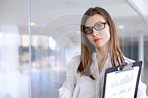 Modern business woman standing and keeping papers in the office with copy space area