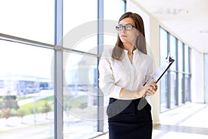 Modern business woman standing and keeping papers in the office with copy space area