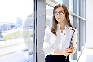 Modern business woman standing and keeping papers in the office with copy space area