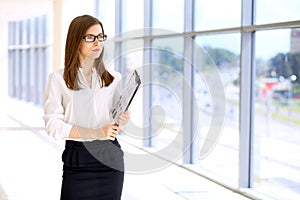 Modern business woman standing and keeping papers in the office with copy space area