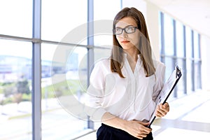 Modern business woman standing and keeping papers in the office with copy space area