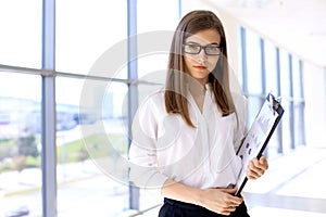 Modern business woman standing and keeping papers in the office with copy space area