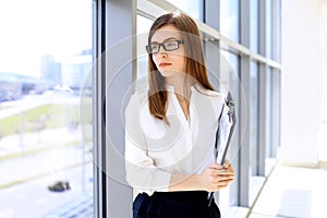 Modern business woman standing and keeping papers in the office with copy space area