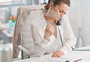 Modern business woman talking phone in office
