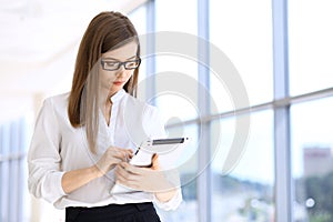 Modern business woman typing on laptop computer while standing in the office before meeting or presentation