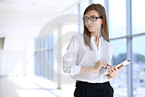 Modern business woman typing on laptop computer while standing in the office before meeting or presentation
