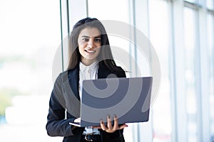 Modern business woman typing on laptop while standing in the office