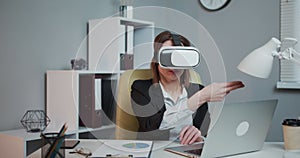 Modern business woman wearing virtual reality glasses in office. Young girl using VR goggles in office. Pretty woman