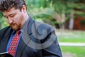Modern businessman of confident middle agedn in full suit holding digital tablet and looking