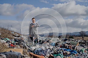 Modern businessman on landfill, consumerism versus pollution concept.