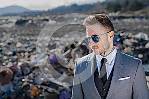 Modern businessman on landfill, consumerism versus pollution concept.