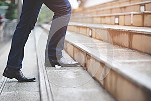 Modern businessman working close-up legs walking up the stairs in modern city.