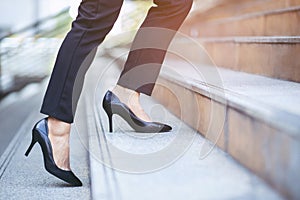 Modern businesswoman working woman close up legs walking up the stairs in modern city in rush hour to work in office a hurry. Duri