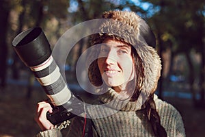 Modern camera with a large lens in hand of young photographer girl and ready to take photo.