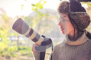 Modern camera with a large lens in hand of young photographer girl and ready to take photo.