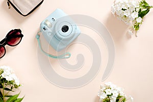 Modern camera, sunglasses, white flowers on pastel pink color background. Top view, tender minimal flat lay style composition.