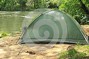 Modern camping tent on riverbank