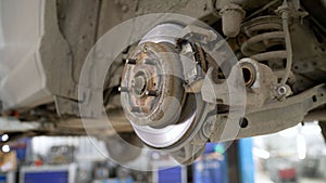 A modern car in a car service on a lift with a wheel removed. Elements of the brake system and suspension. Brake pad