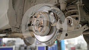 A modern car in a car service on a lift with a wheel removed. Elements of the brake system and suspension. Brake pad