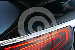 Modern car headlight of a black luxury car close up