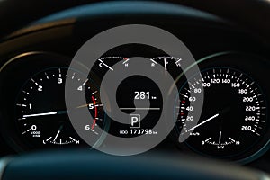 Modern car illuminated dashboard closeup. White arrows on Speedometer