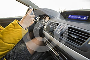 Modern car interior with driver female hands on steering wheel. Safe driving concept