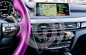Modern car interior. Pink steering wheel with media phone control buttons. Navigation screen. Multimedia system background. Car in
