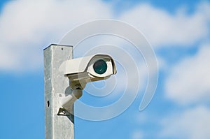 Modern CCTV camera on a iron pole against blue sky