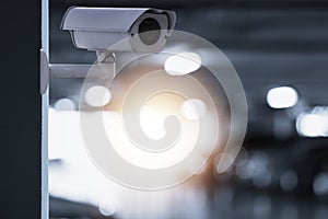 Modern of CCTV camera for monitoring surveillance and security on the wall with car park background photo